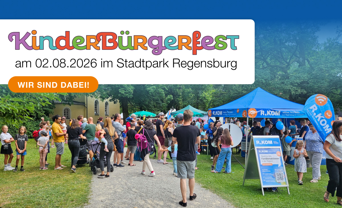 Ein bunt geschmückter Event-Stand der R-KOM unter blauem Himmel.